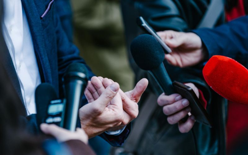 A group of people holding microphones and speaking into them.