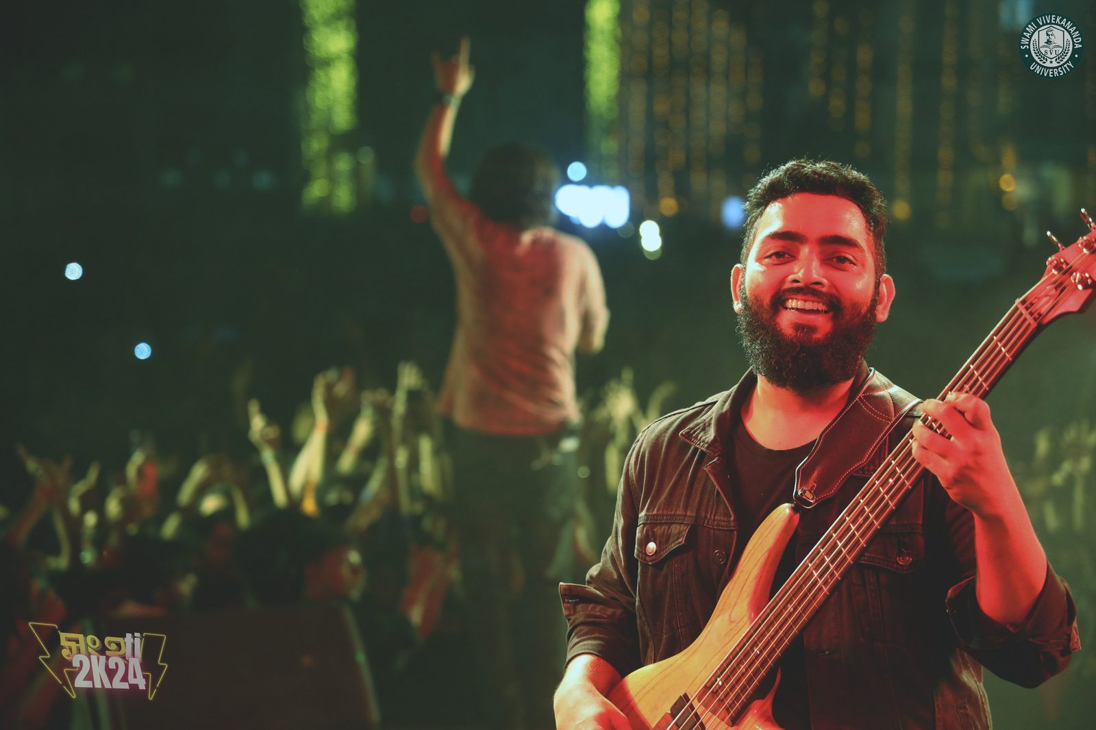 The bassist grinning straight at the camera from the front of the stage, the singer working the crowd behind him