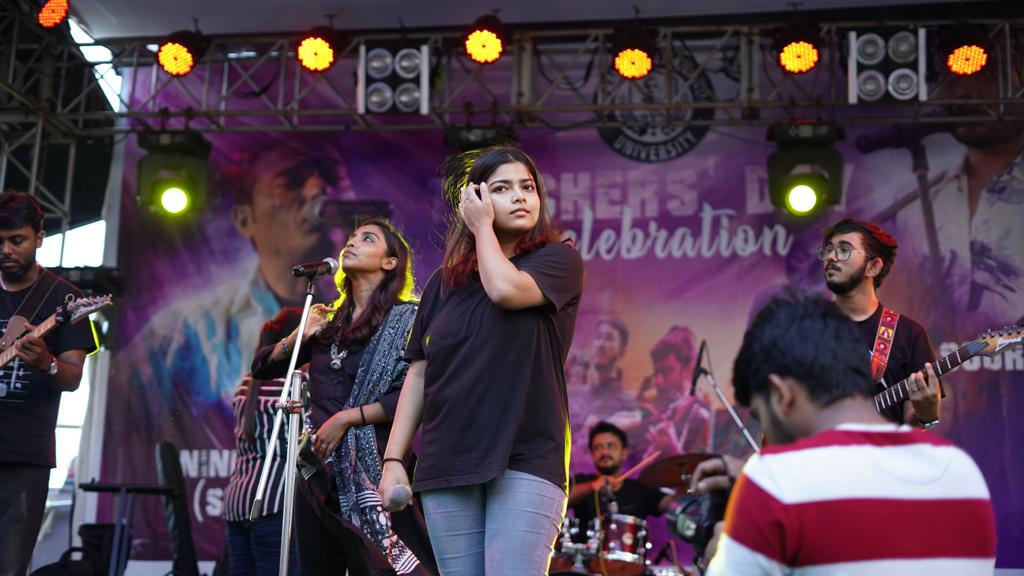 The full student band mid-set on the open-air stage, two vocalists out in front