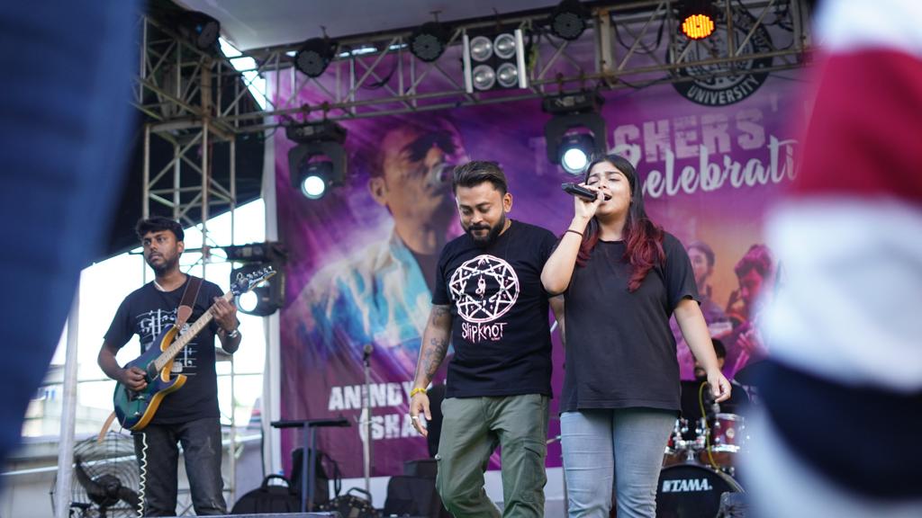 Two singers trading lines at the front of the stage with the bassist behind them