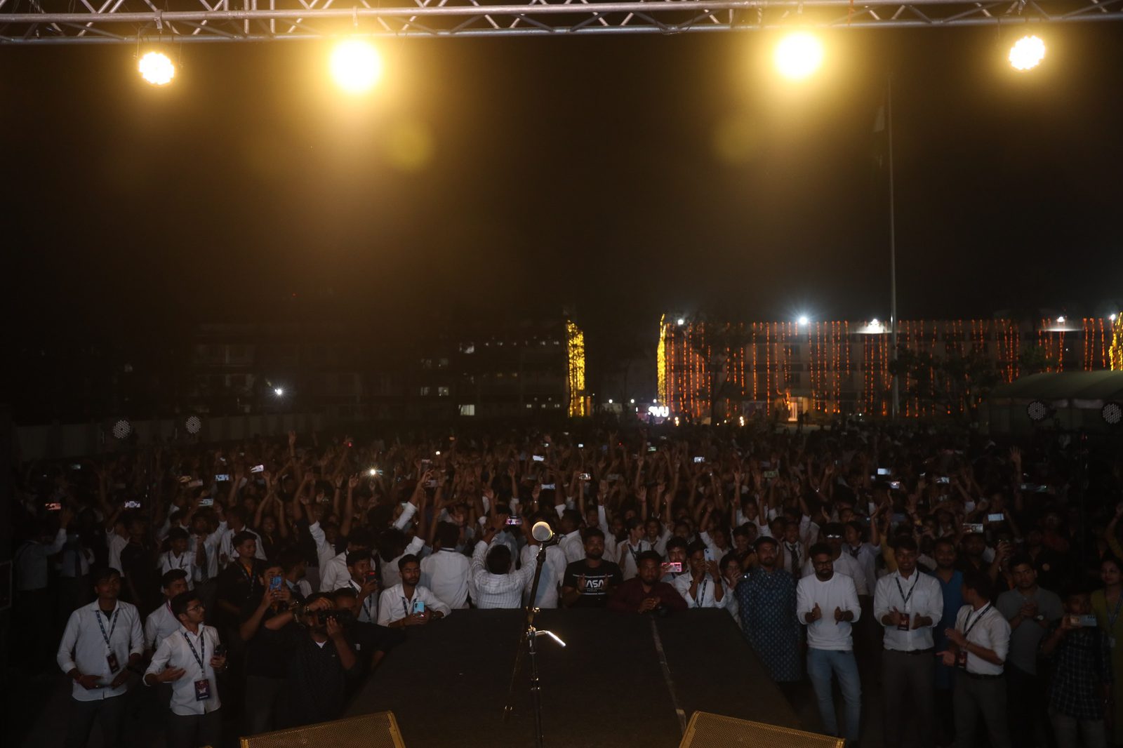 The view out from the stage over the whole crowd, phones up, the campus lit behind them
