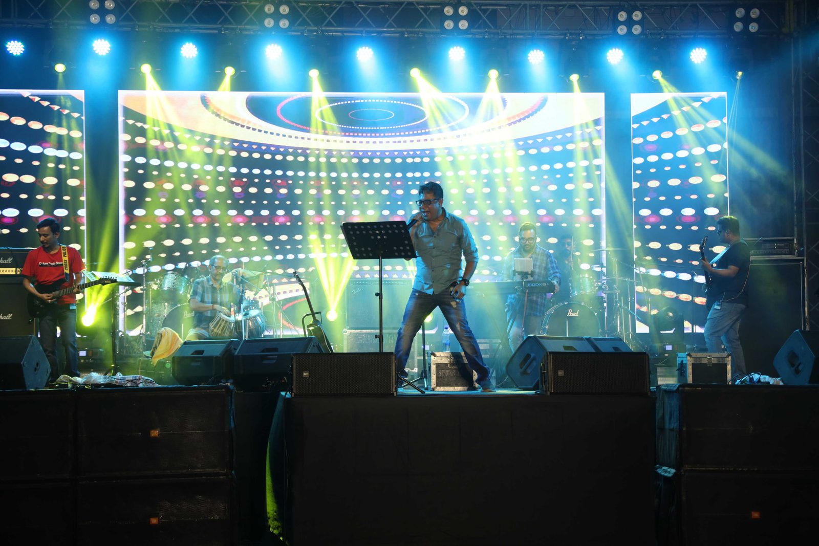 Wide view of the stage in blue and green light, the dotted LED wall running the full width