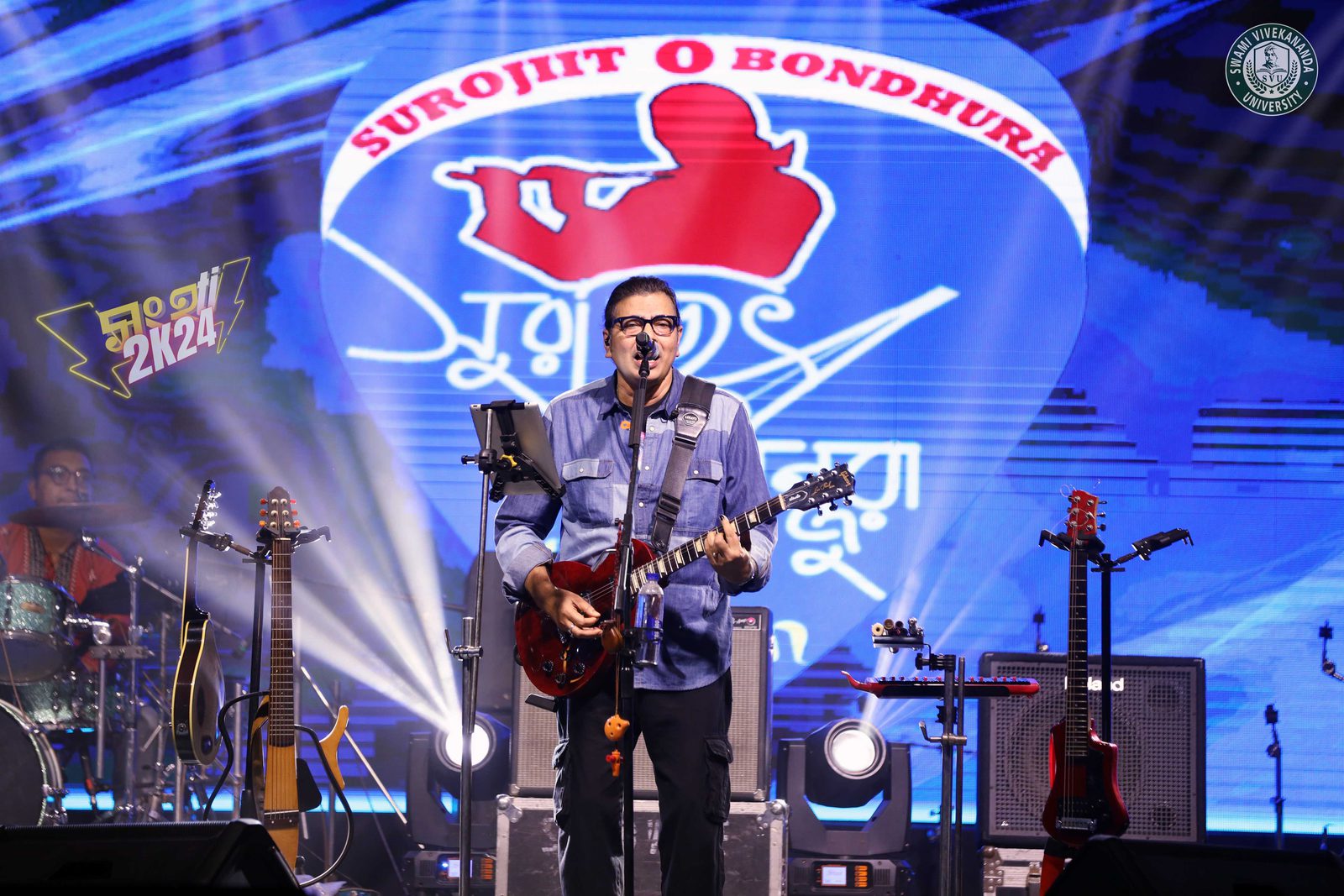 The frontman singing at the mic with a red semi-hollow guitar, the band's name filling the screen behind