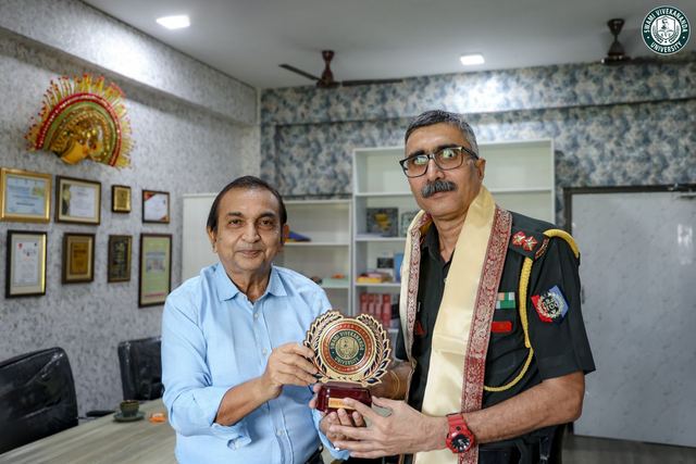 An Army officer, wearing a ceremonial shawl, receiving a University memento from an official