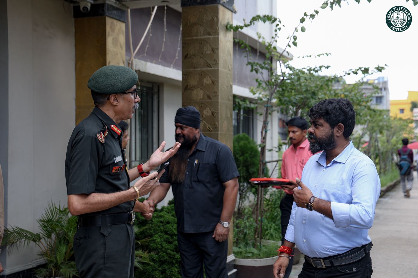 The visiting officer in conversation with University staff outside a campus building
