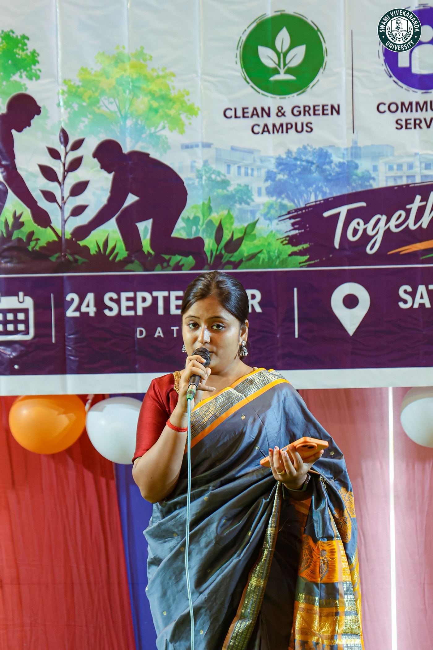 A member of staff speaking at the microphone beside the NSS Day backdrop